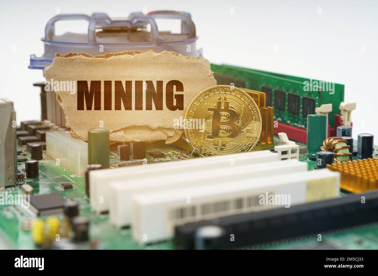 Crypto - business concept. On the motherboard lies a bitcoin coin and a cardboard sign with the inscription - Mining Stock Photo
