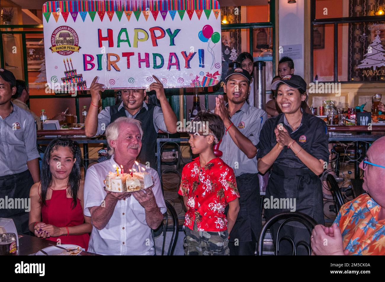 60 year old western man (dual citizen, Irish - American) celebrates his 60th birthday, Tawandang micro-brewery, Phnom Penh, Cambodia. © Kraig Lieb Stock Photo
