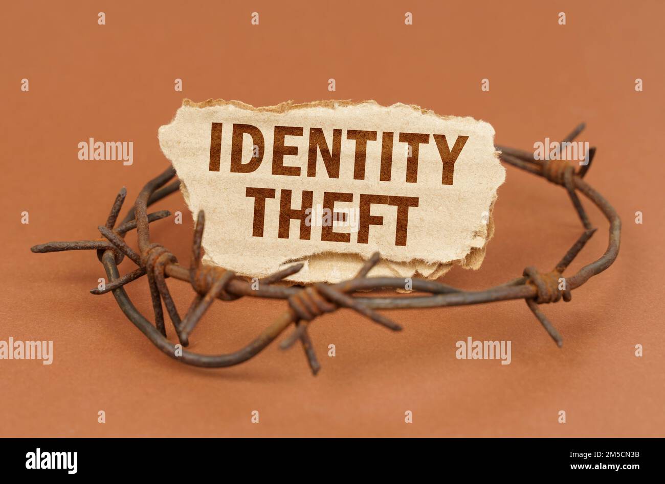 The concept of law and crime. On a brown surface, barbed wire and a cardboard sign with the inscription - Identity theft Stock Photo