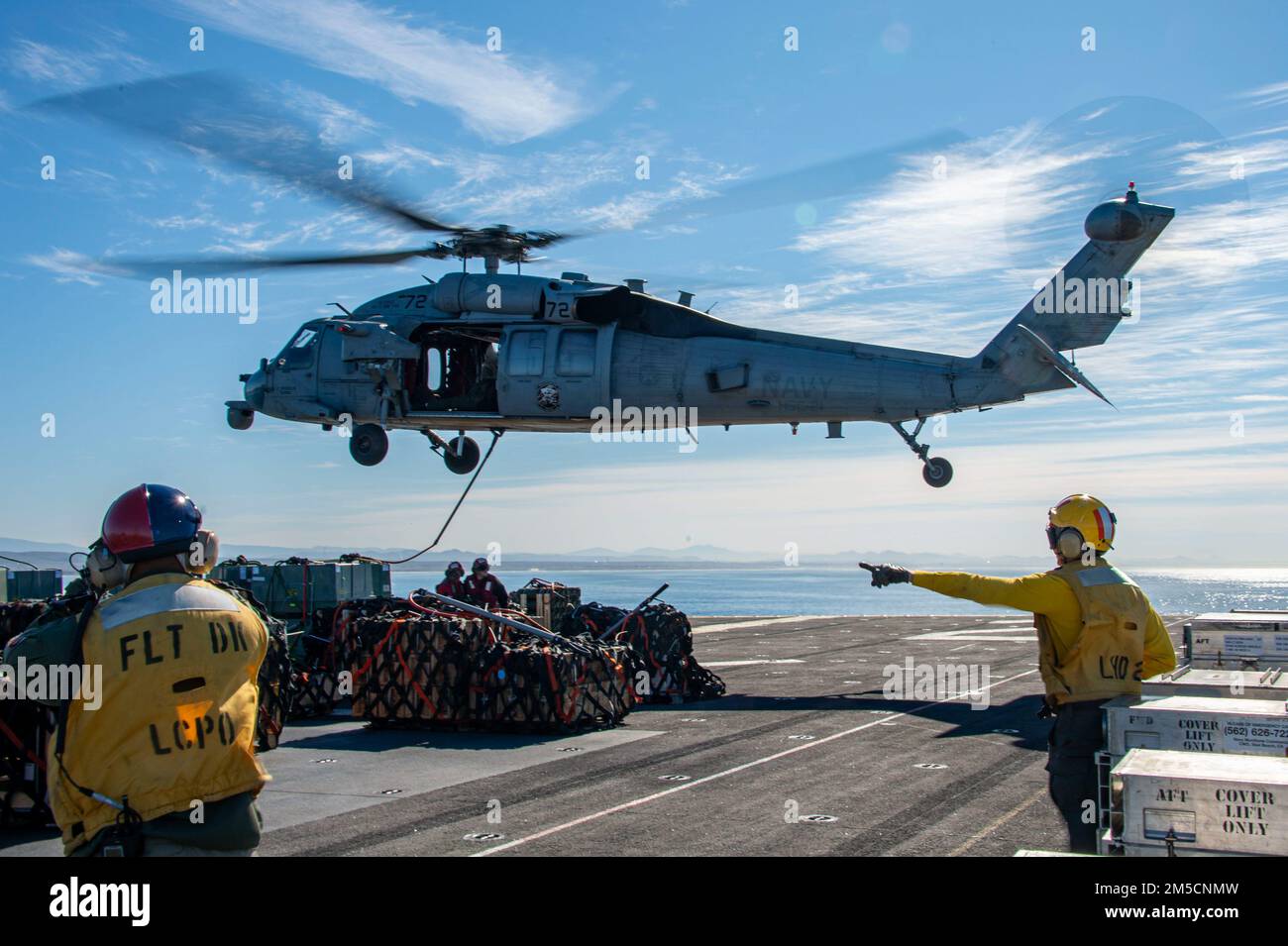 PACIFIC OCEAN (March 2, 2022) Sailors assigned to amphibious assault ship USS Essex (LHD 2) conduct ammo offload with an MH-60S Sea Hawk helicopter attached to Helicopter Sea Combat Squadron (HSC) 21 aboard Essex, March 2, 2022. Sailors and Marines of Essex Amphibious Ready Group (ARG) and the 11th Marine Expeditionary Unit (MEU) are underway conducting routine operations in U.S. 3rd Fleet. Stock Photo