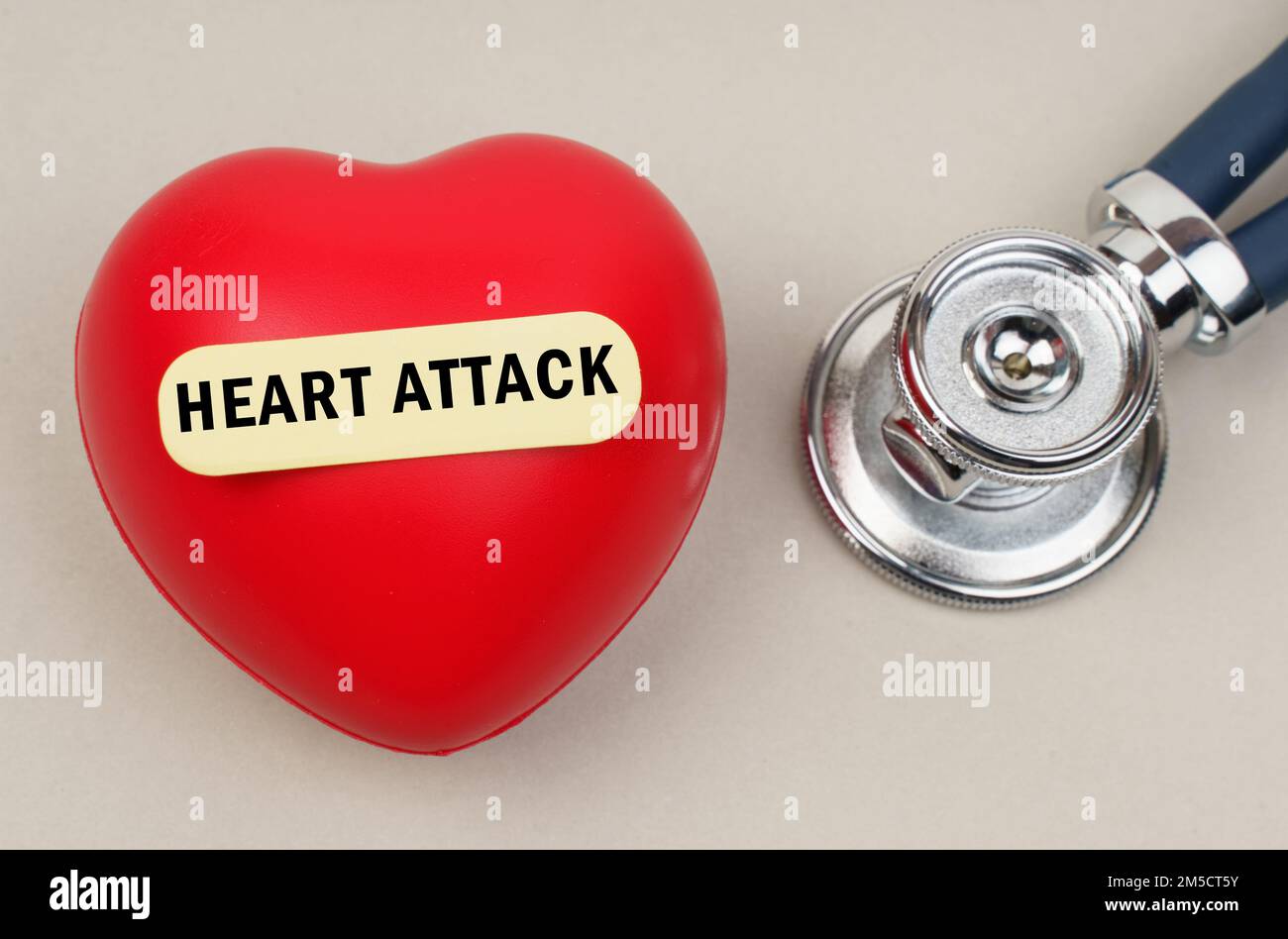 Medicine concept. Near the stethoscope lies a heart on which a sticker is pasted with the inscription - HEART ATTACK Stock Photo
