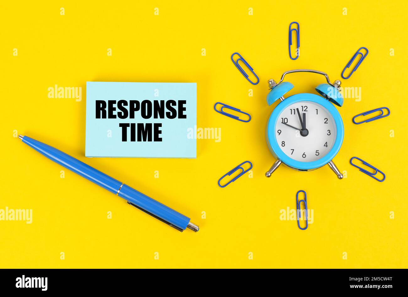 Business and technology concept. On the yellow surface there is an alarm clock, a pen and stickers with the inscription - Response Time Stock Photo