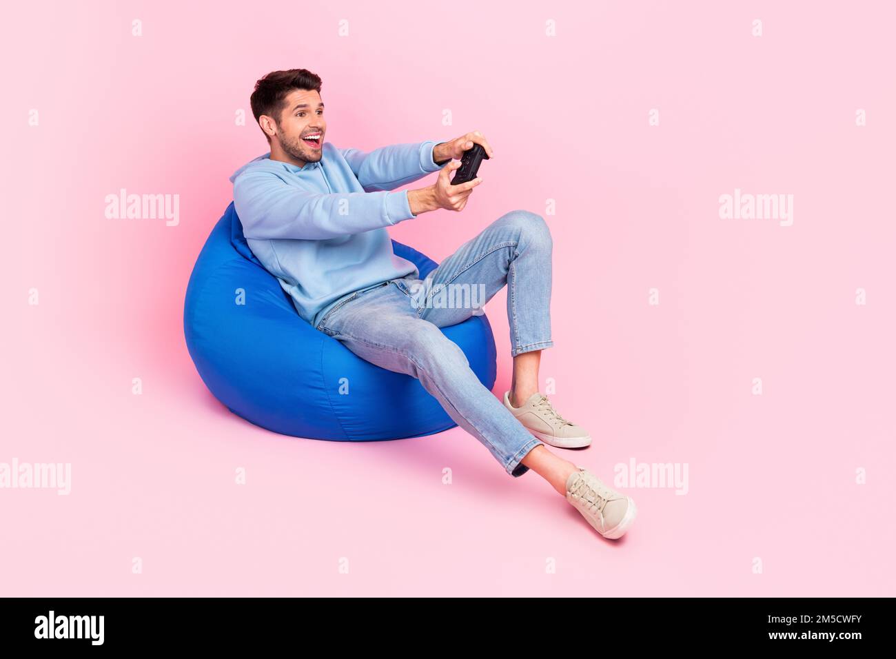 Photo of positive stylish man have relax rest home free time playing gta game empty space isolated on pink color background Stock Photo