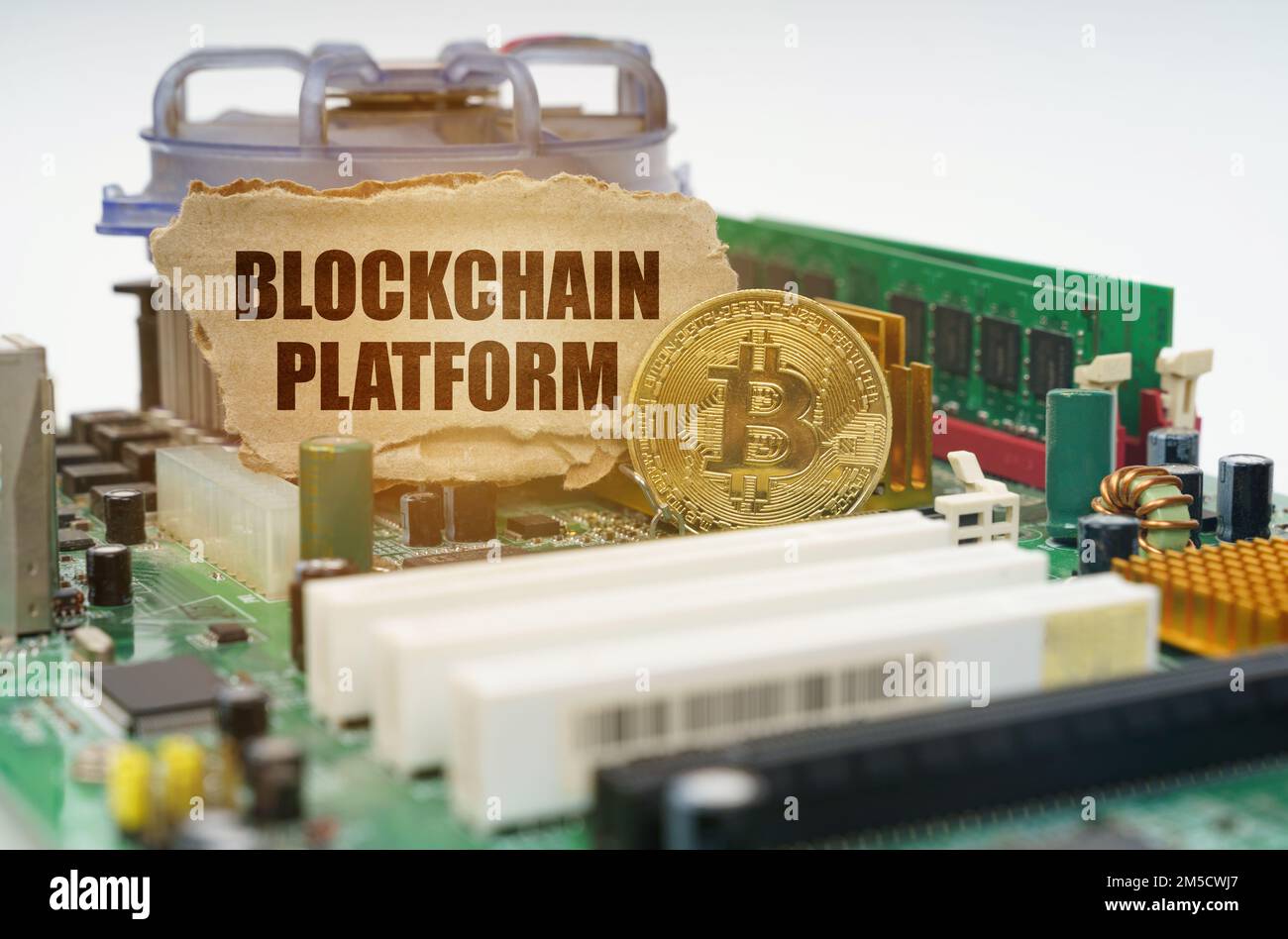 Crypto - business concept. On the motherboard lies a bitcoin coin and a cardboard sign with the inscription - Blockchain platform Stock Photo