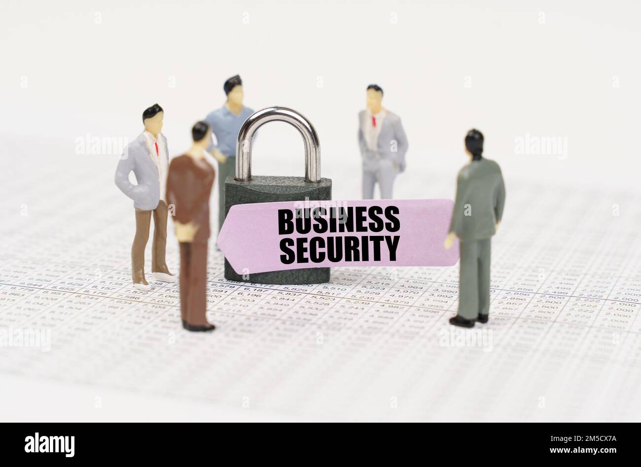 The concept of security in business. There are figures of people on business reports, a padlock with a sticker on which it is written - Business secur Stock Photo