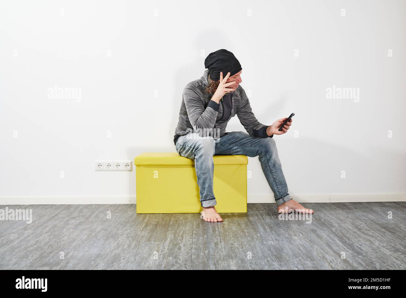 Man using his smartphone on a green box Stock Photo