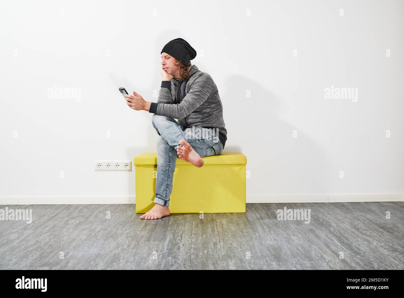Man using his smartphone on a green box Stock Photo