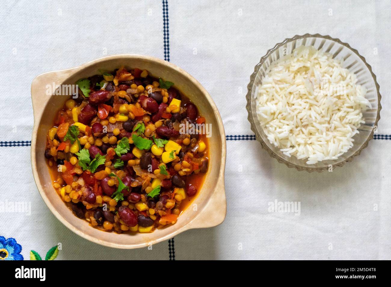 Three bean vegetarian chili. Made with black, white and red beans and corn. Accompanied with white rice. Stock Photo