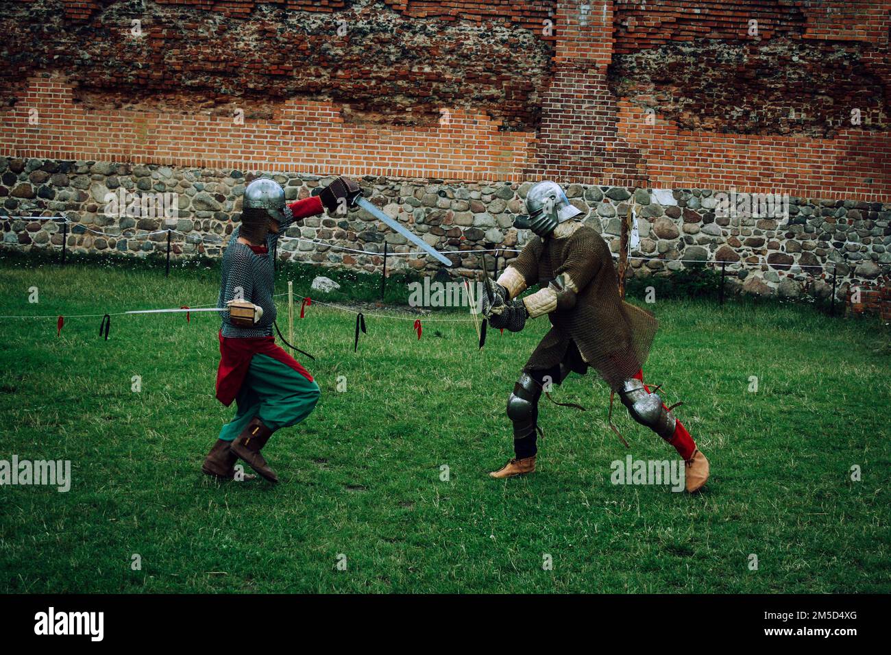 Sword fight of two knights in helmets and chain mail armor in scenery of medieval castle Stock