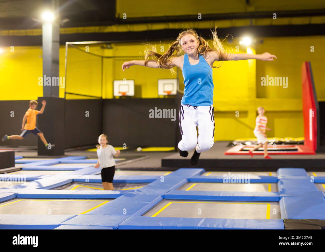 Teenage girl bouncing on trampoline in indoor amusement park Stock