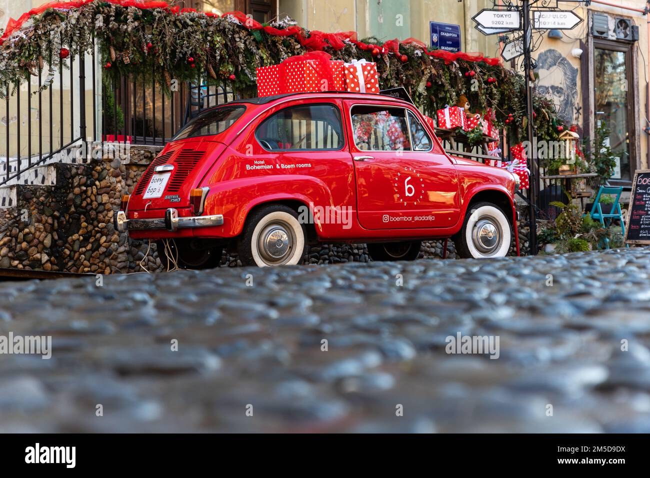 Belgrade, Serbia - December 23, 2022: Oldtimer showcase red car with Christmas presents on the roof in the Skadarlija street in Belgrade, Serbia Stock Photo