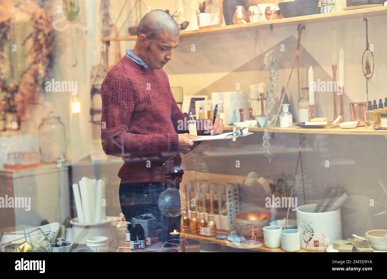 Pricing his products for profit. a young man checking stock in his store. Stock Photo