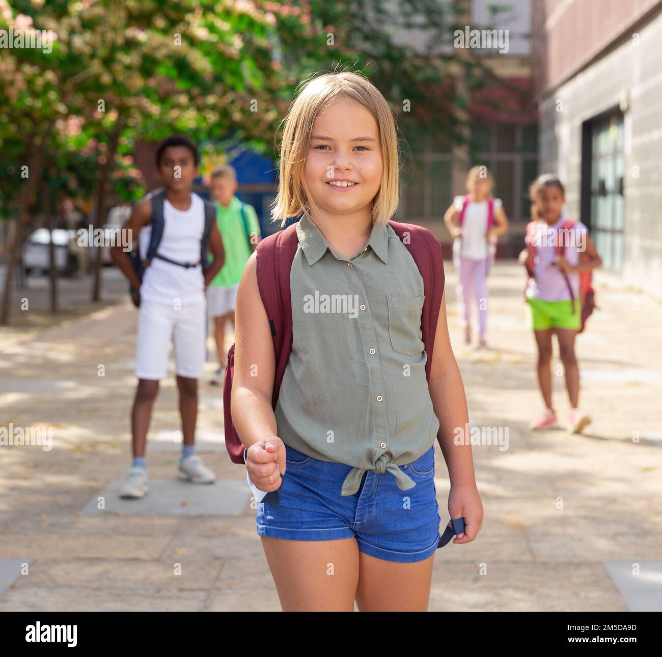 Schoolgirl with backpack walking down street to school Stock Photo Alamy