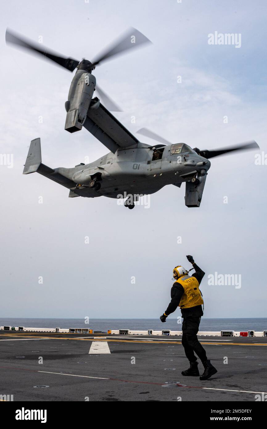 PHILIPPINE SEA (March. 4, 2022) Aviation Boatswain’s Mate (handling) Airman Daunte Babino, from Houston, assigned to the forward-deployed amphibious assault ship USS America (LHA 6), directs an MV-22B Osprey tiltrotor aircraft from the 31st Marine Expeditionary Unit (MEU) to take off from the ship’s flight deck. America, lead ship of the America Amphibious Ready Group, along with the 31st MEU, is operating in the U.S. 7th Fleet area of responsibility to enhance interoperability with allies and partners and serve as a ready response force to defend peace and stability in the Indo-Pacific region Stock Photo