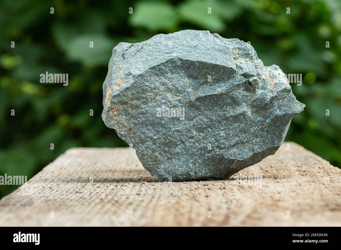 A Piece of Gray, Slate Metamorphic Rock Sample on Wooden Background Stock Photo