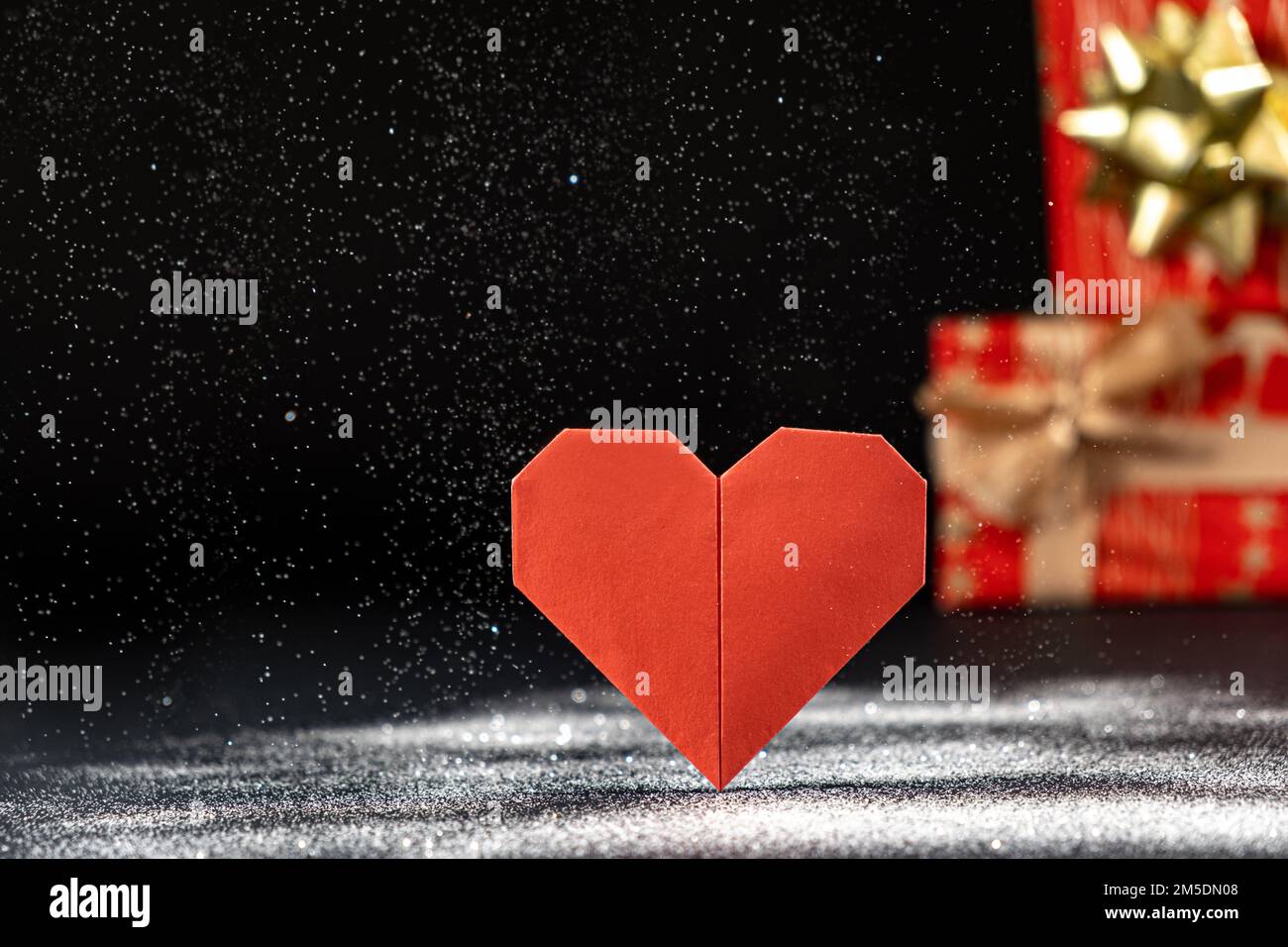 Red heart and valentine's day gifts, sequins, snow falling, space for text, copy space. Stock Photo
