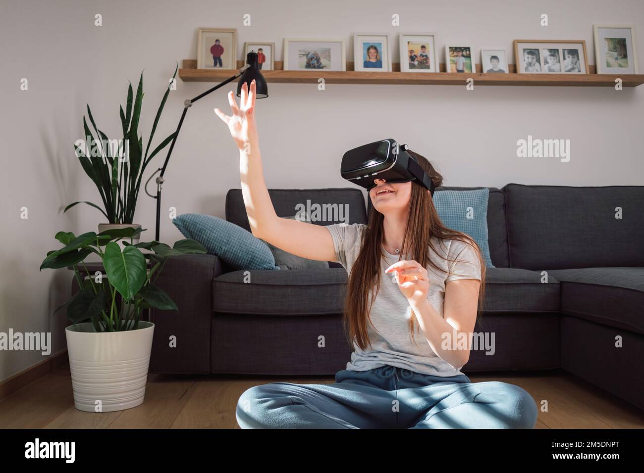 Young Caucasian woman with virtual reality headset, enjoying interacting in computer generating environment Stock Photo