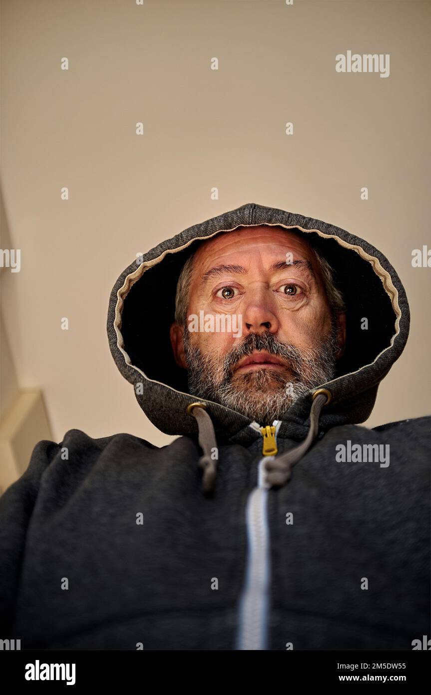worried middle aged man in hooded jacket, looking down Stock Photo