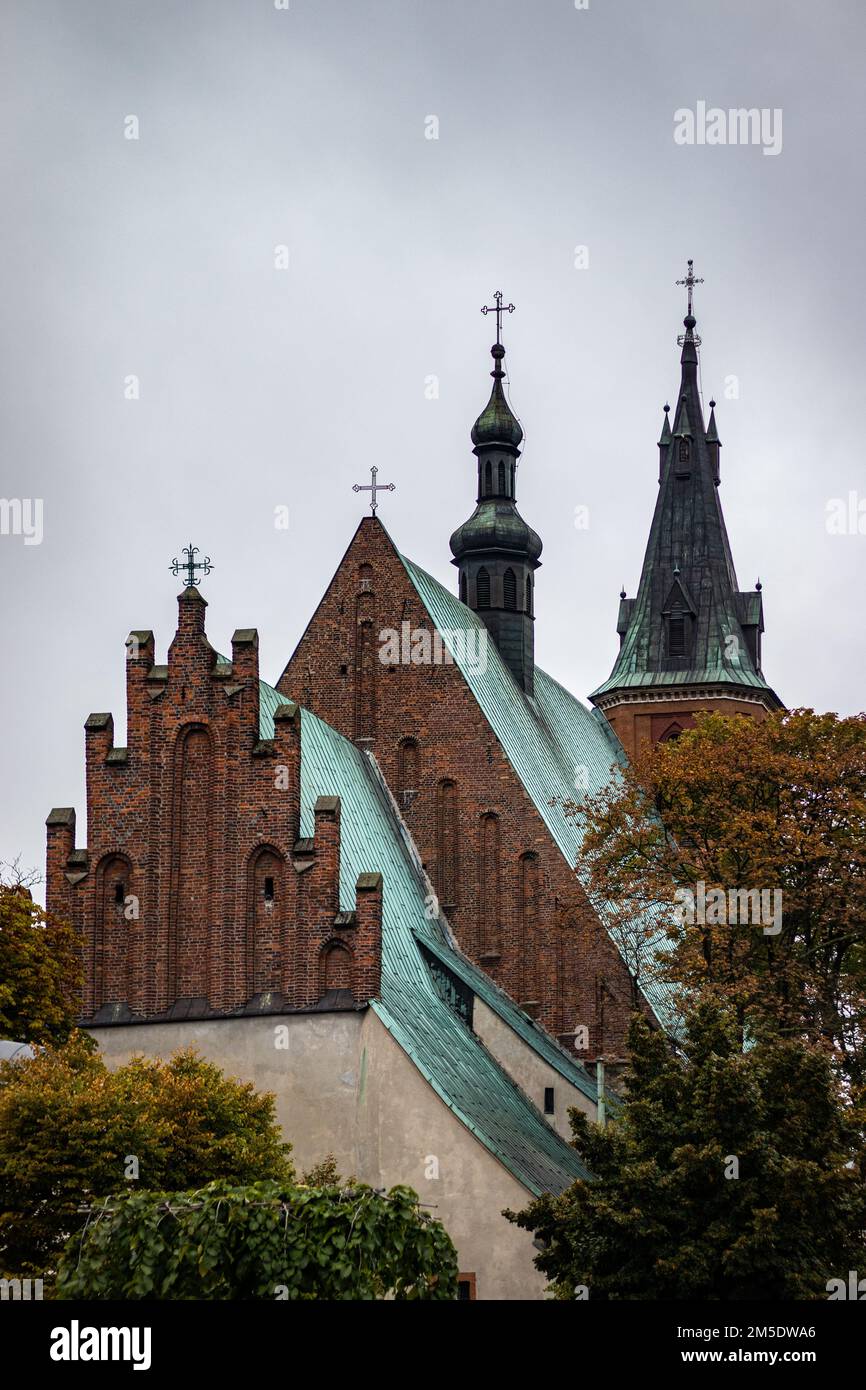 The facade of Basilica in Olkusz, Poland with trees under sunset sky Stock Photo