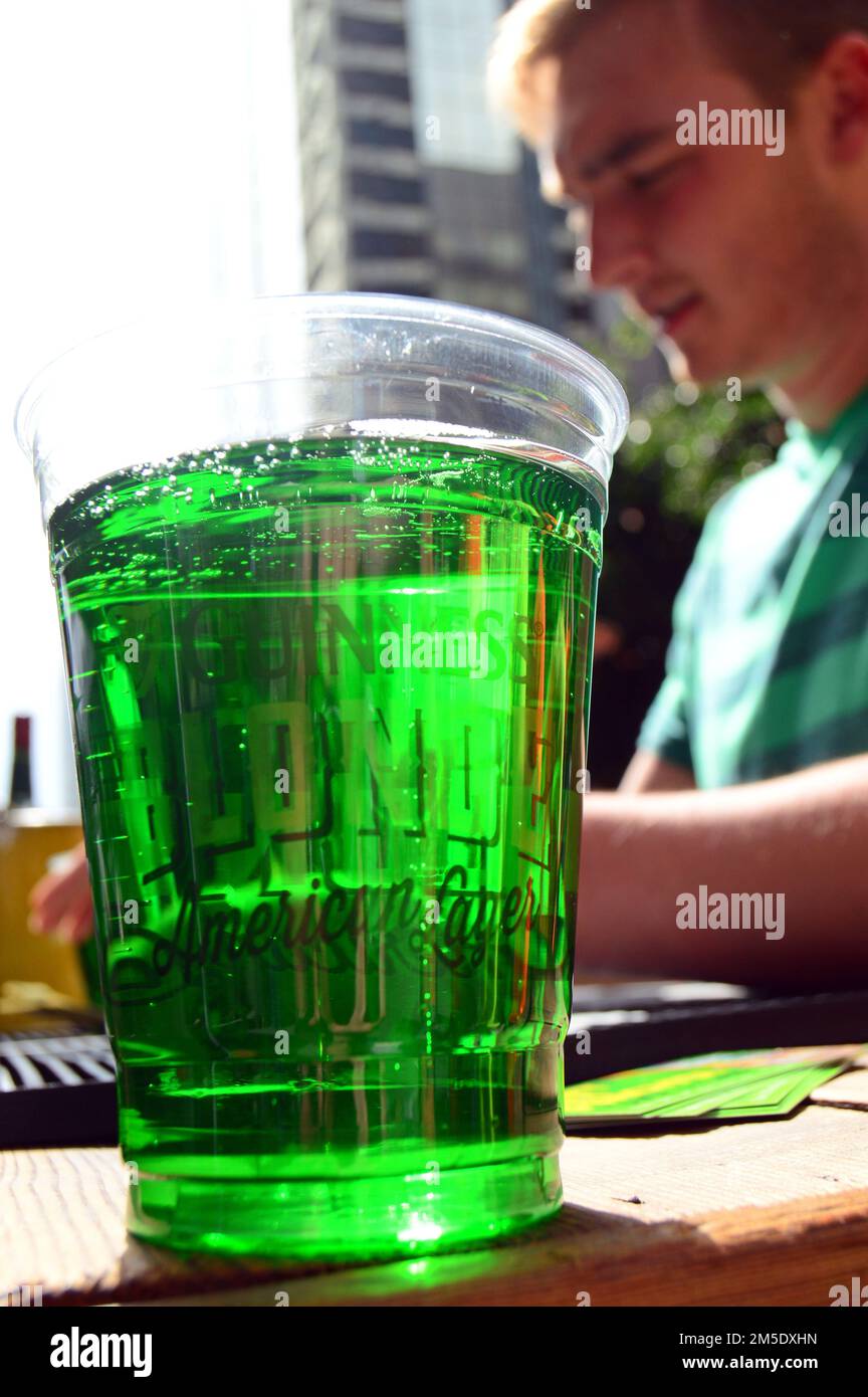 An adult man orders a glass of green beer at an outdoor bar on St Patrick’s Day Stock Photo