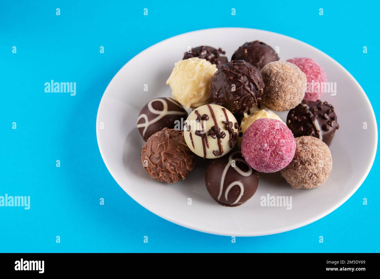 photo round chocolate candies on a plate on a blue background Stock Photo