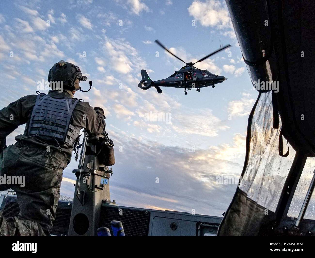 A member of U.S. Naval Special Warfare Task Unit Europe (NSWTU-E) guides a host nation MEDEVAC air asset on final approach to conduct a hoist at sea during Exercise Trojan Footprint 22 in Lithuania, May 3, 2022. Trojan Footprint is the premier Special Operations Forces (SOF) exercise in Europe that focuses on fortifying military readiness, cultivating trust and developing lasting relationships which promote peace and stability throughout Europe. Stock Photo