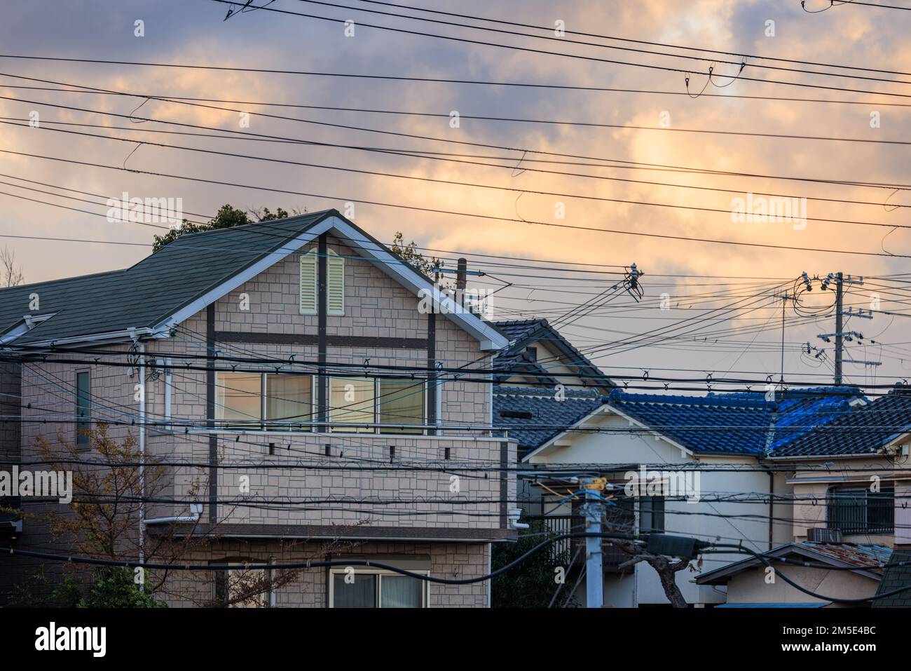Electrical wires cross suburban homes with sunrise color in clouds Stock Photo