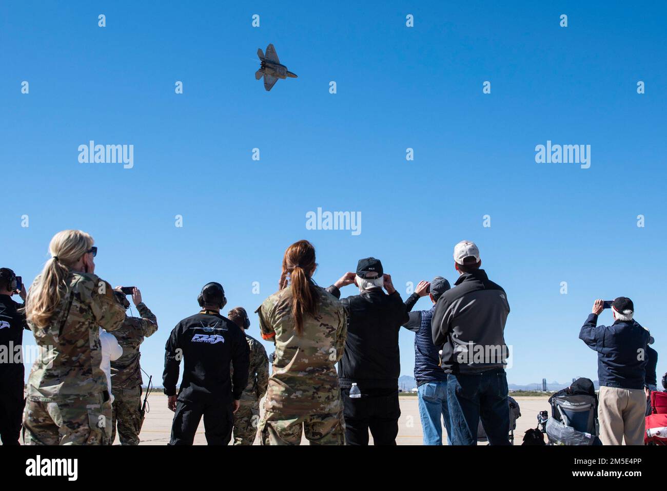 Members of the U.S. military and Heritage Flight attendees watch the F-22 Raptor Demonstration Team performance during the Heritage Flight Training Course at Davis-Monthan Air Force Base, Arizona, March 6, 2022. During the event, civilian warbird pilots and current Air Force demonstration pilots trained together in preparation for the 2022 air show season. Stock Photo