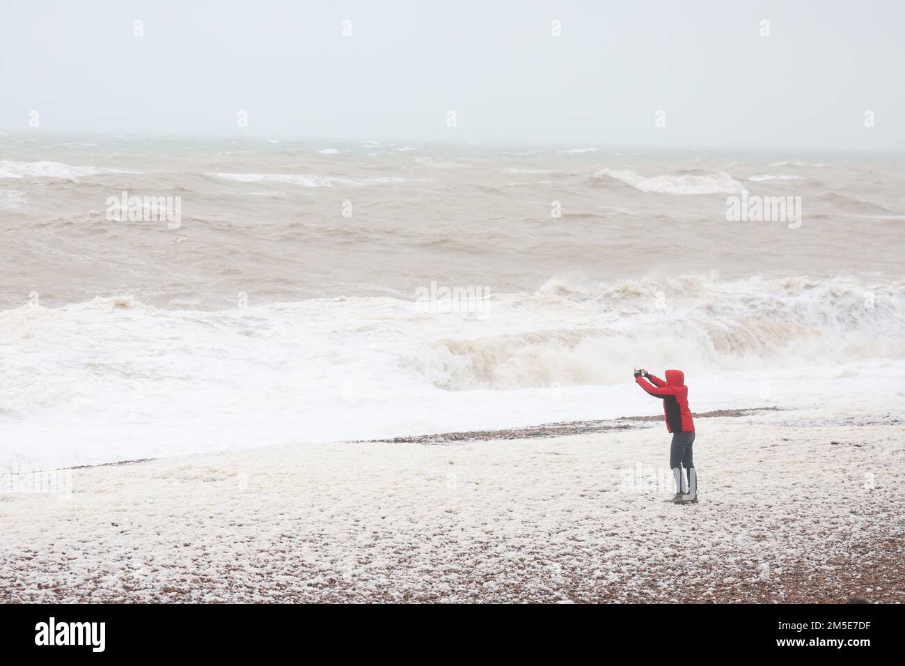 Brighton, UK. 28th Dec, 2022. A man takes a selfie on the beach as waves crash onto Brighton beach as the high winds and rain continue to batter the South Coast. Credit: James Boardman/Alamy Live News Stock Photo