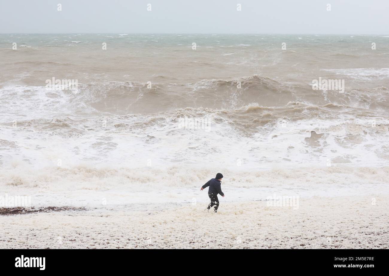 Brighton, UK. 28th Dec, 2022. A child plays dangerously close to the waters edge as waves crash onto Brighton beach as the high winds and rain continue to batter the South Coast. Credit: James Boardman/Alamy Live News Stock Photo