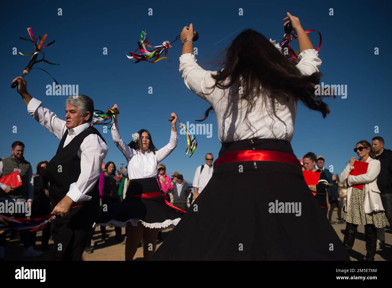 Participants dressed in traditional costumes are seen dancing before