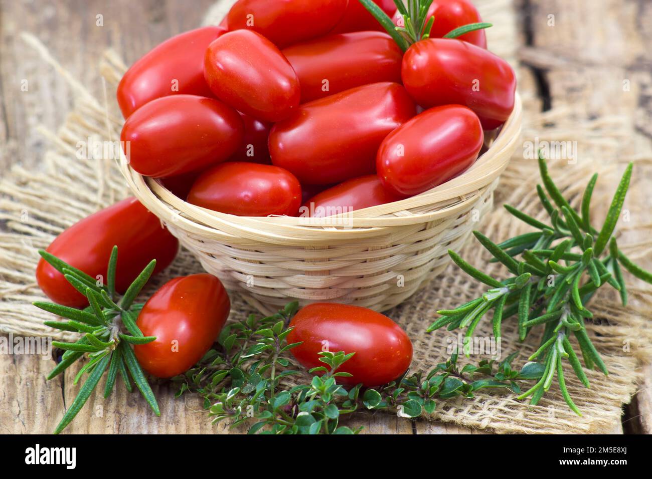 mini roma tomatoes and herbs on wooden background Stock Photo - Alamy