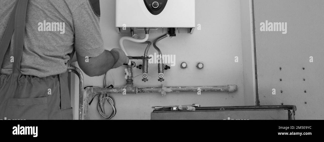 Image of a plumber at work repairing and installing a gas boiler. Horizontal banners Stock Photo