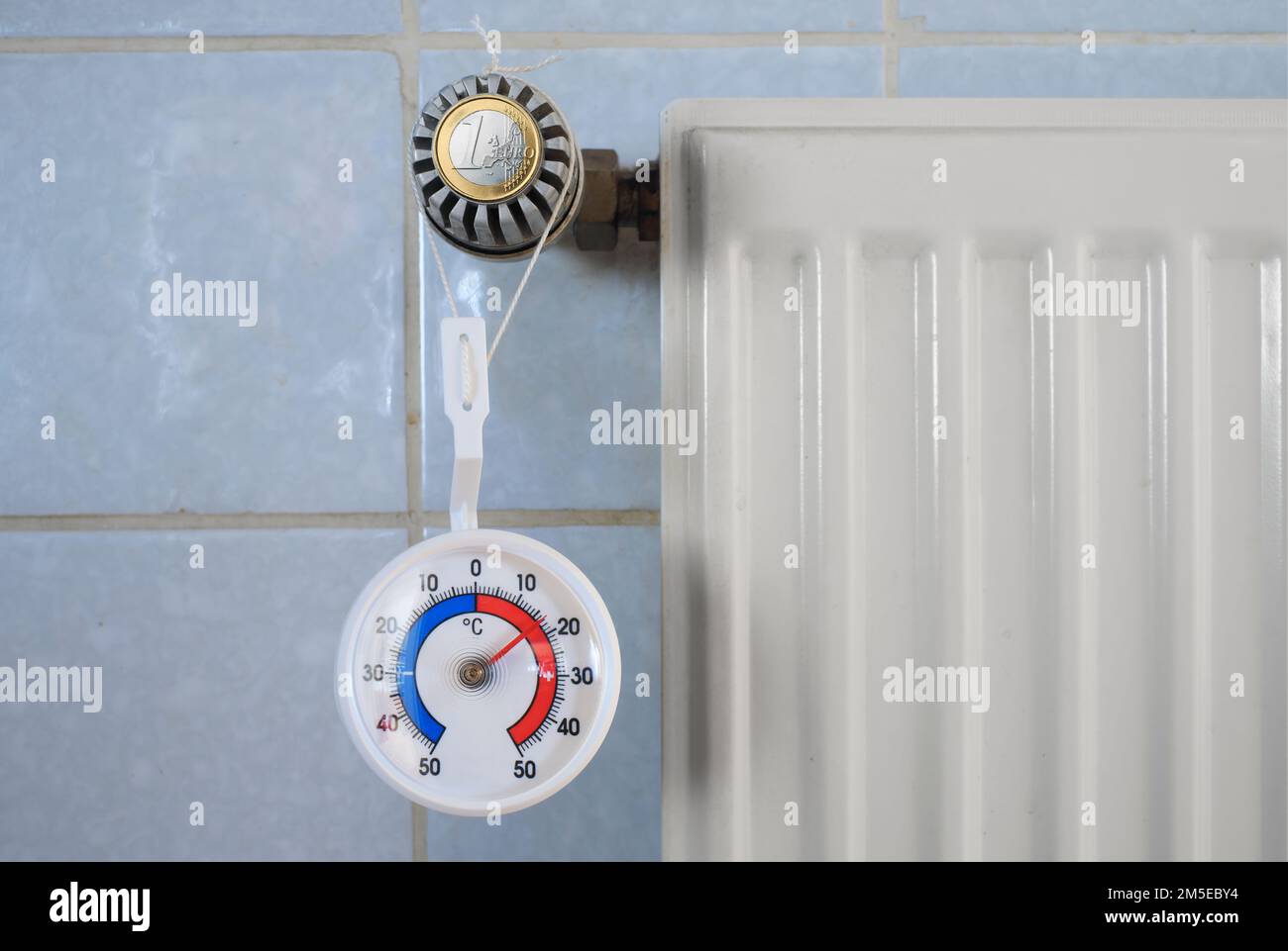 Radiator valve, euro coin and thermometer showing low temperature, rising heating and energy costs due to shortage of heating gas and oil Stock Photo
