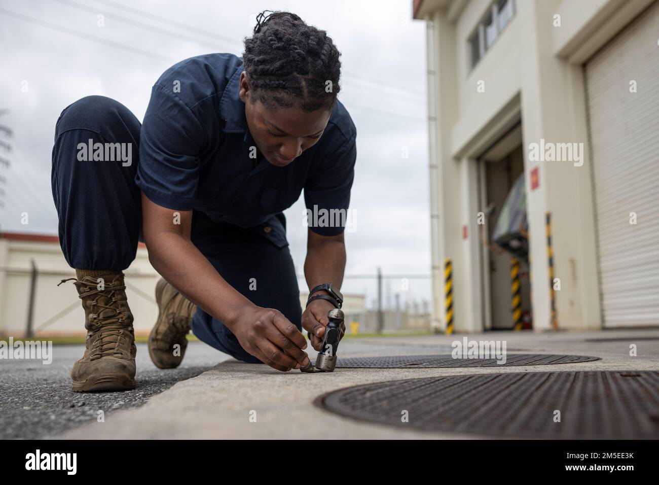 U.S. Marine Corps Cpl. Crystal Davis, an automotive maintenance technician with 3d Landing Support Battalion, Combat Logistics Regiment 3, 3d Marine Logistics Group, flattens a piece of metal with a hammer to repair a 7-ton truck starter on Camp Foster, Okinawa, Japan, Mar. 7, 2022. Davis, a Spanishtown, Jamaica native, joined the Marine Corps in 2019. Now at the rank of Corporal, she continues to be a diligent leader by striving to mirror her mother's guidance and wisdom towards her Marines. Stock Photo