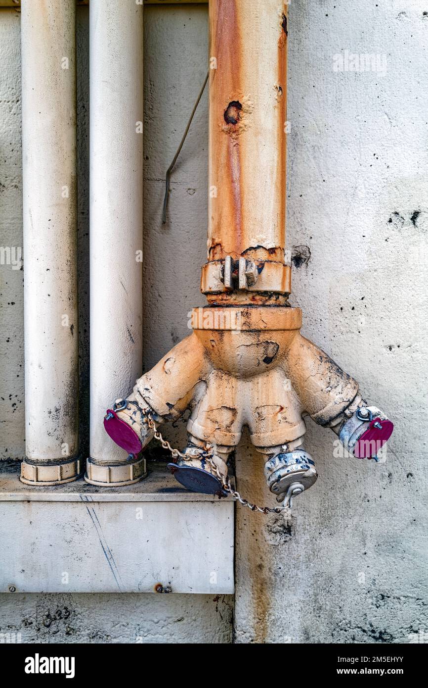 Four connections feeding into a single standpipe on an exterior wall of