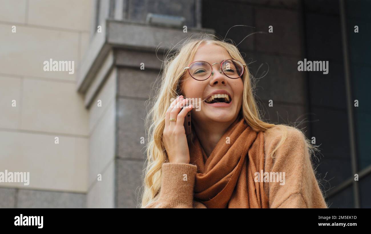 Happy emotional Caucasian smiling laughing girl talking mobile phone cheerful woman smile laugh friendly talk smartphone call cellphone conversation Stock Photo
