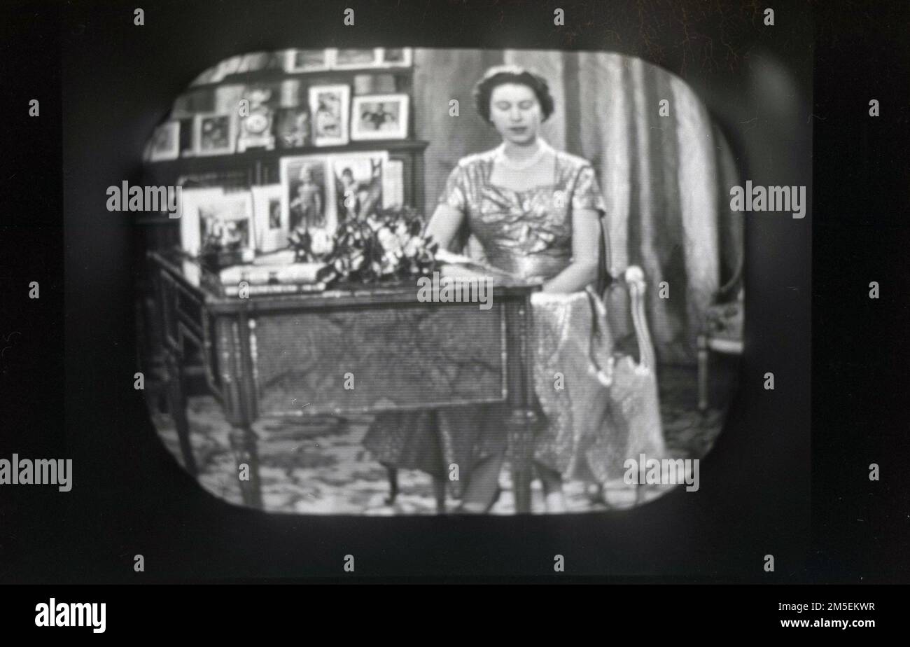 1957, historical, Queen Elizabeth II giving her Christmas message on BBC televsion. The 1957 Christmas Broadcast was an historic event, as it was the first to be televised, being broadcast live from the Long Library at Sandringham, Norfolk, England, UK. The tradition of a British monarch delivering a christmas message began with a radio broadcast by King George V in 1932 via the BBC's Empire Service. Stock Photo