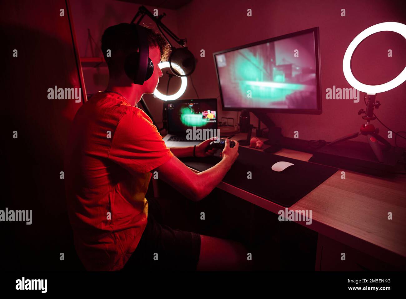Gamer playing with a console and a computer screen indoors Stock Photo