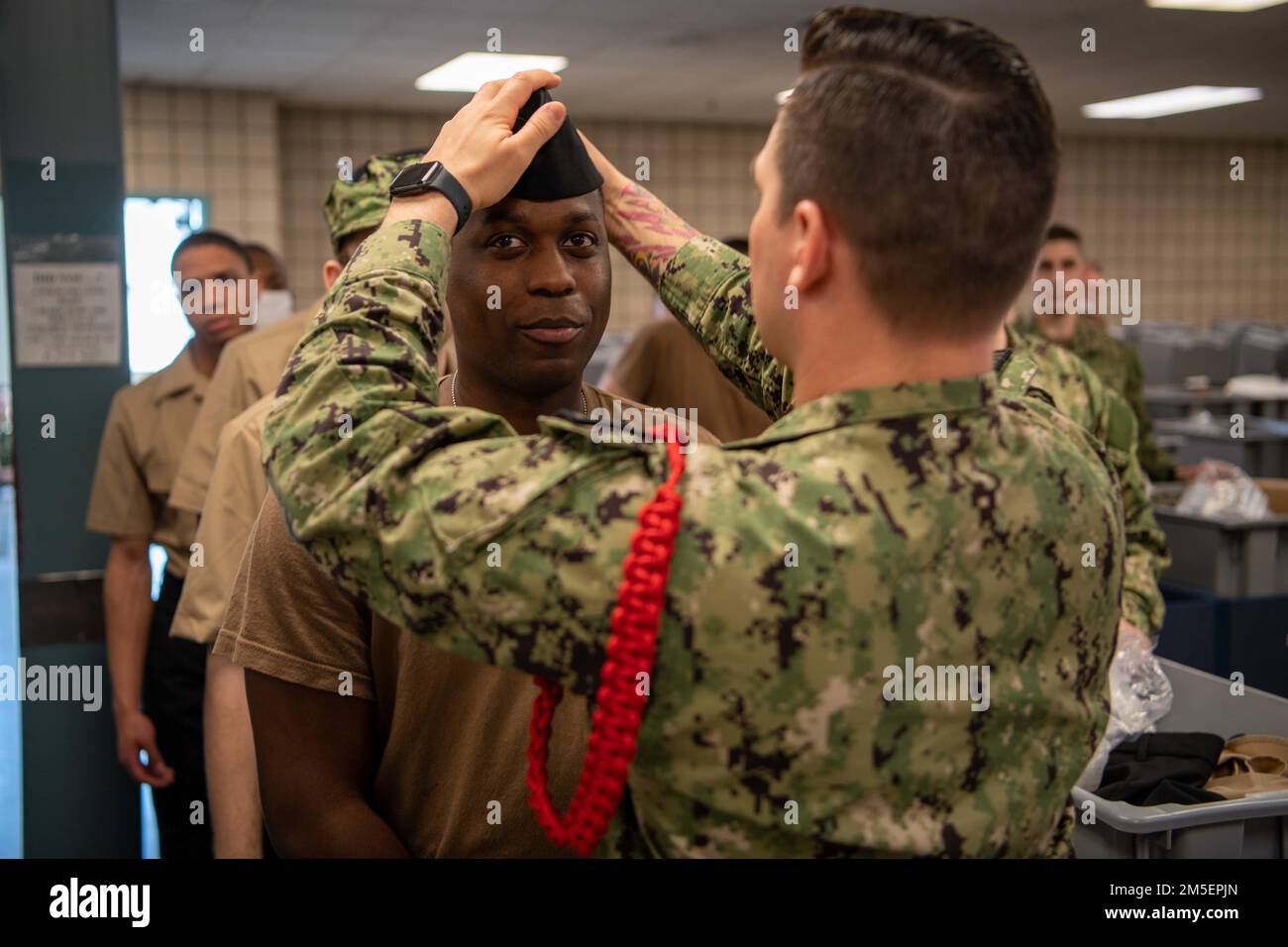 A recruit division commander assigned to Recruit Training Command fits a cover for a recruit in his division. More than 40,000 recruits train annually at the Navy’s only boot camp. Stock Photo