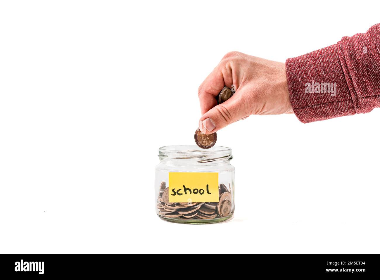 Close up male putting money into a glass jar, moneybox, penny or piggy bank. Saving money euro coin for  school, college or university. Saving money. Stock Photo