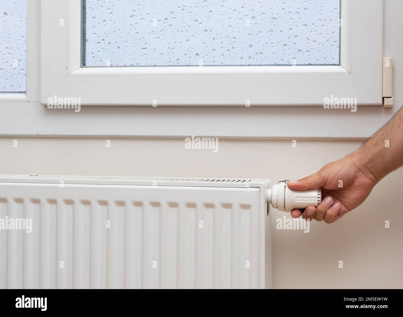 A man's hand adjusting the temperature of a radiator Stock Photo - Alamy