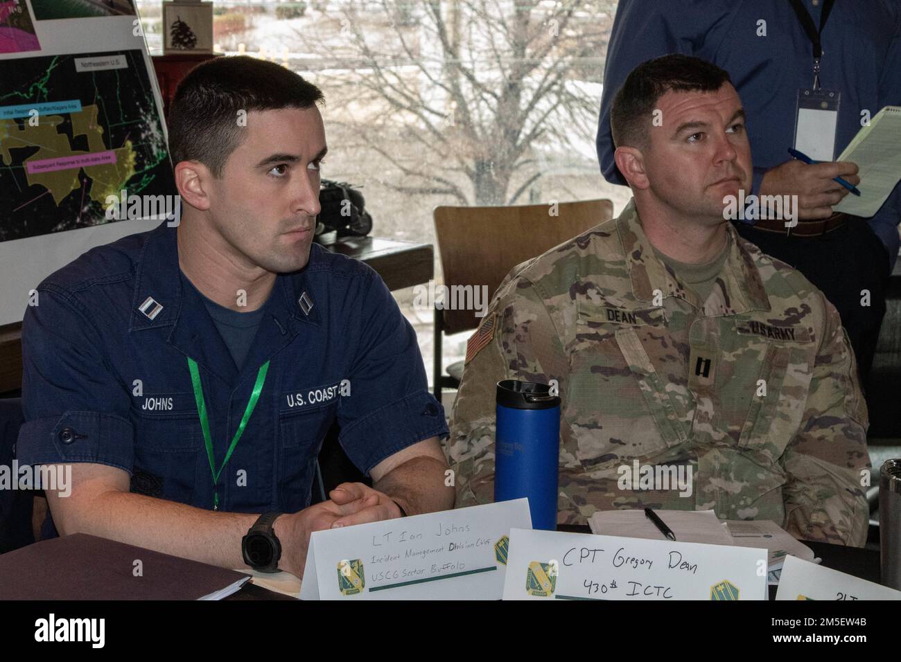 U.S. Army Reserve Capt. Greg Dean, operations officer with 430th Inland Cargo Transfer Company, 313th Movement Control Battalion, right, teams with Lt. Ian Johns, incident management chief with the U.S. Coast Guard, during exercise Cyber Impact 22 in Buffalo, New York, Mar. 9, 2022. From Mar. 8-10, 2022, the Cyber Impact exercise includes over 150 participants from 12 Army National Guard, two Army Reserve units, as well as local, state, federal, private sector, academic, and Canadian partners. The Michigan National Guard's 46th Military Police Command provides command and control to DoD servic Stock Photo