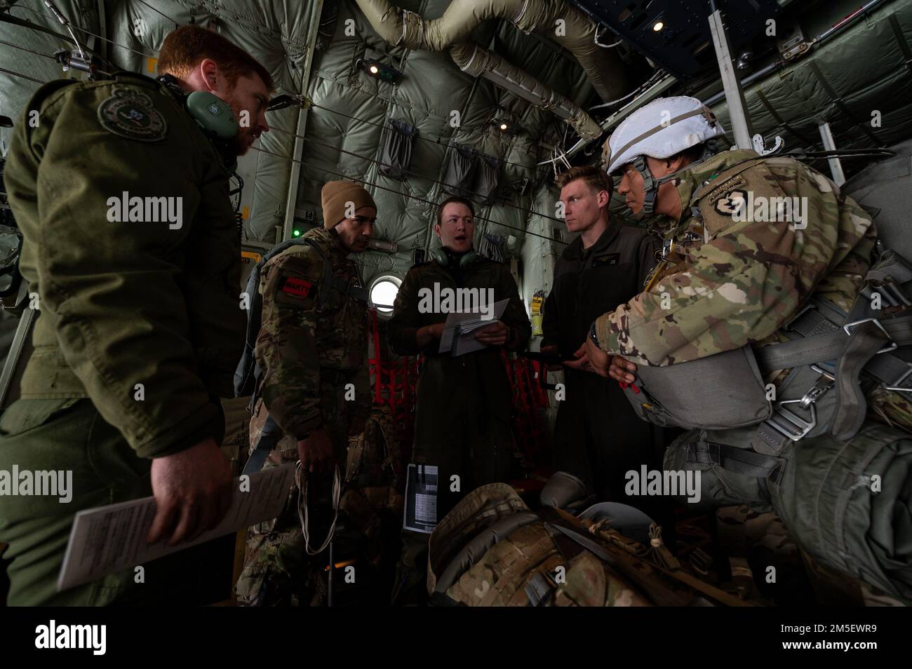 Royal Canadian Air Force Capt. Jake Balfe (center), an RCAF CC-130J Hercules aircraft first officer assigned to the 436 Transport Squadron, gives a mission brief to aircrew members and U.S. Army Soldiers, assigned to the 1st Squadron, 40th Cavalry Regiment, 4th Brigade combat team, 25th Infantry Division, U.S. Army Alaska, prior to jumping into Joint Pacific Multinational Readiness Center 22-02 on Joint Base Elmendorf-Richardson, AK, March 9, 2022. JPMRC 22-02 is the first Regional Combat Training Center (HS-CTC) rotation in Alaska. It focuses on Large Scale Combat Operations (LSCO) and is a C Stock Photo