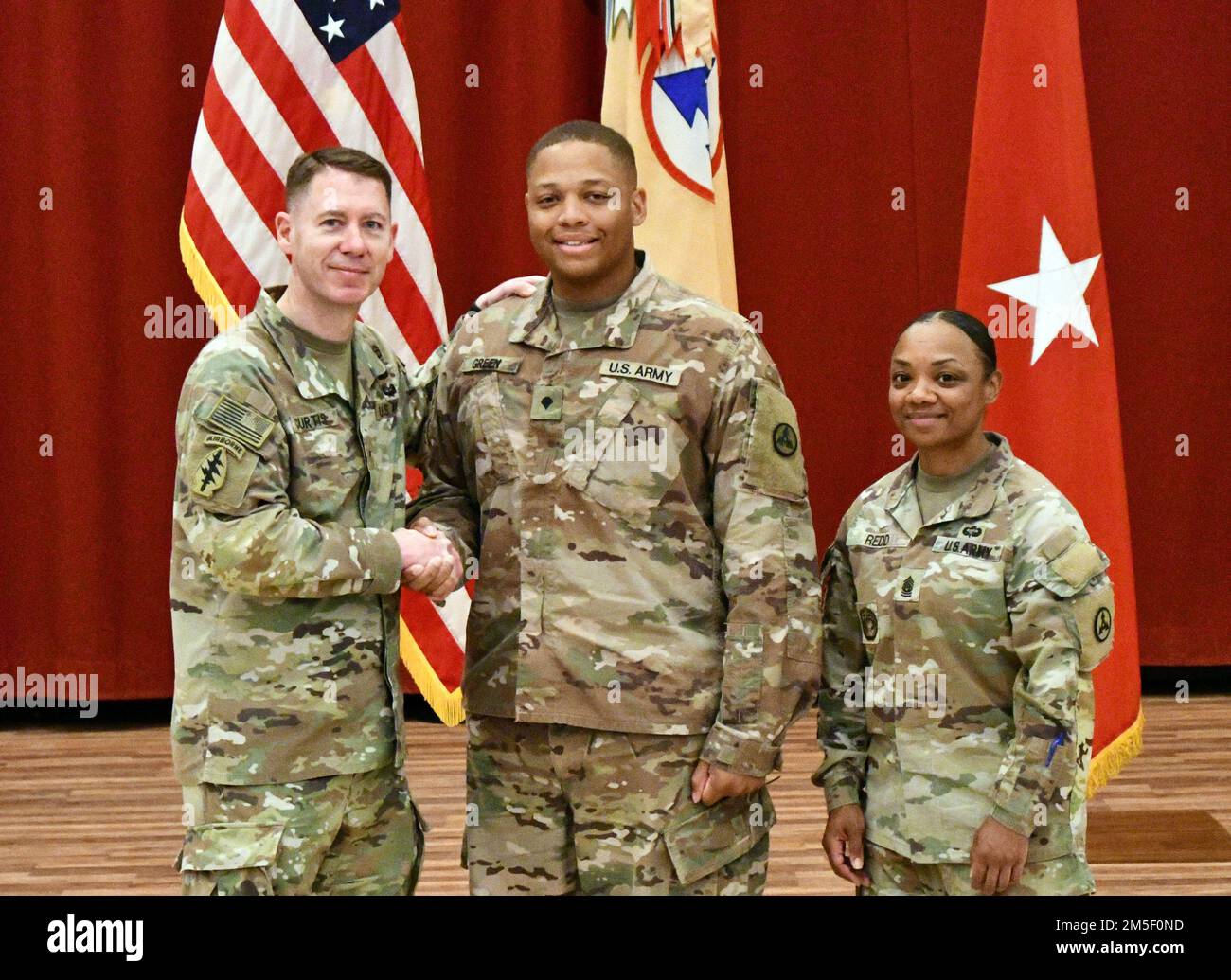 Brig. Gen. Lance G. Curtis, deputy commanding general, 1st Theater Sustainment Command, and commanding general, 3rd Expeditionary Sustainment Command, and Command Sgt. Maj. Phelicea M. Redd, senior enlisted advisor, 1st TSC operational command post and 3rd ESC, pose with Spc. Darius J. Green, an ammunition specialist assigned to 3rd ESC, after presenting him a Shoulder Sleeve Insignia-Former Wartime Service patch during a patching ceremony at Camp Arifjan, Kuwait, Mar. 9, 2022. Curtis and Redd presented patches to more than 20 “Spears Ready” Soldiers for their service in designated combat zone Stock Photo