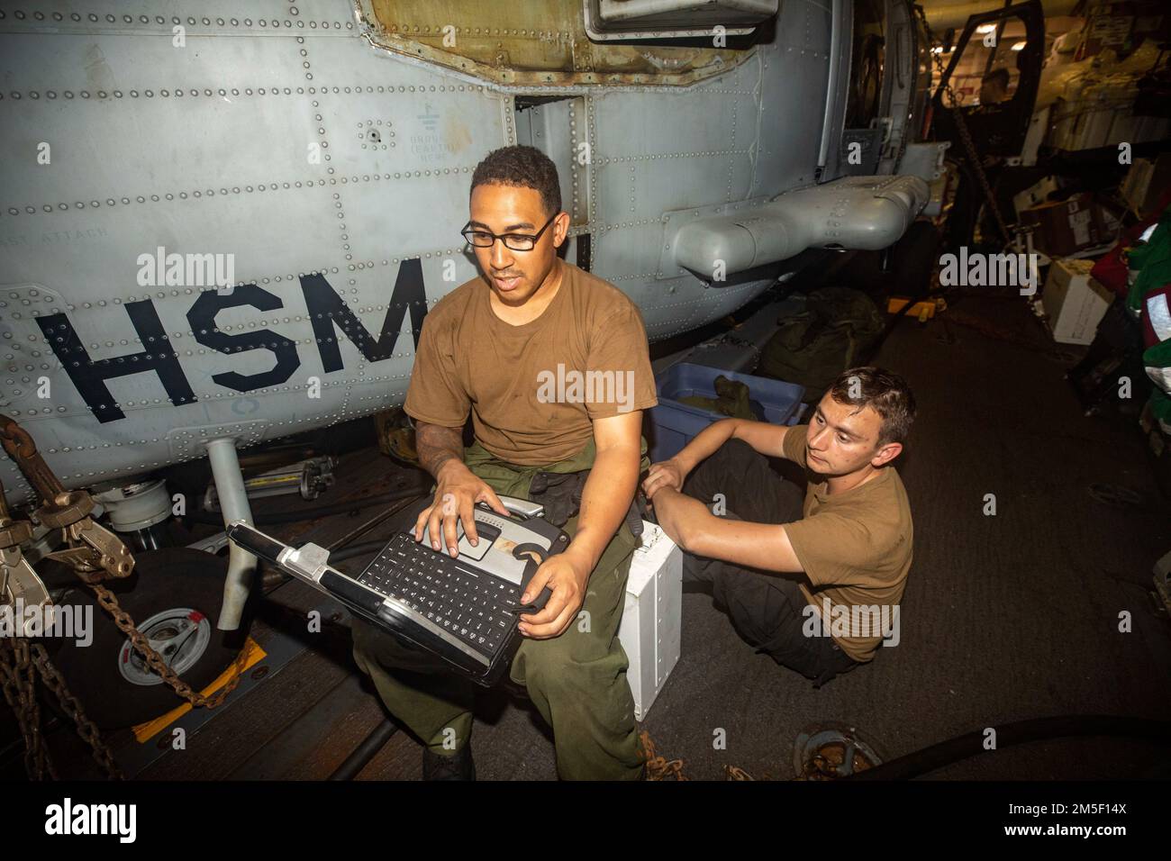 PHILIPPINE SEA (March 9, 2022) Aviation Machinist 3rd Class Tyler John, from Phoenix, Az., and Aviation Machinist Mate 3rd Class Sean Givens, from Texarkana, Texas, conduct maintenance on an MH-60R helicopter aboard Arleigh Burke-class guided-missile destroyer USS Ralph Johnson (DDG 114). Ralph Johnson is assigned to Task Force 71/Destroyer Squadron (DESRON) 15, the Navy’s largest forward-deployed DESRON and the U.S. 7th fleet’s principal surface force. Stock Photo