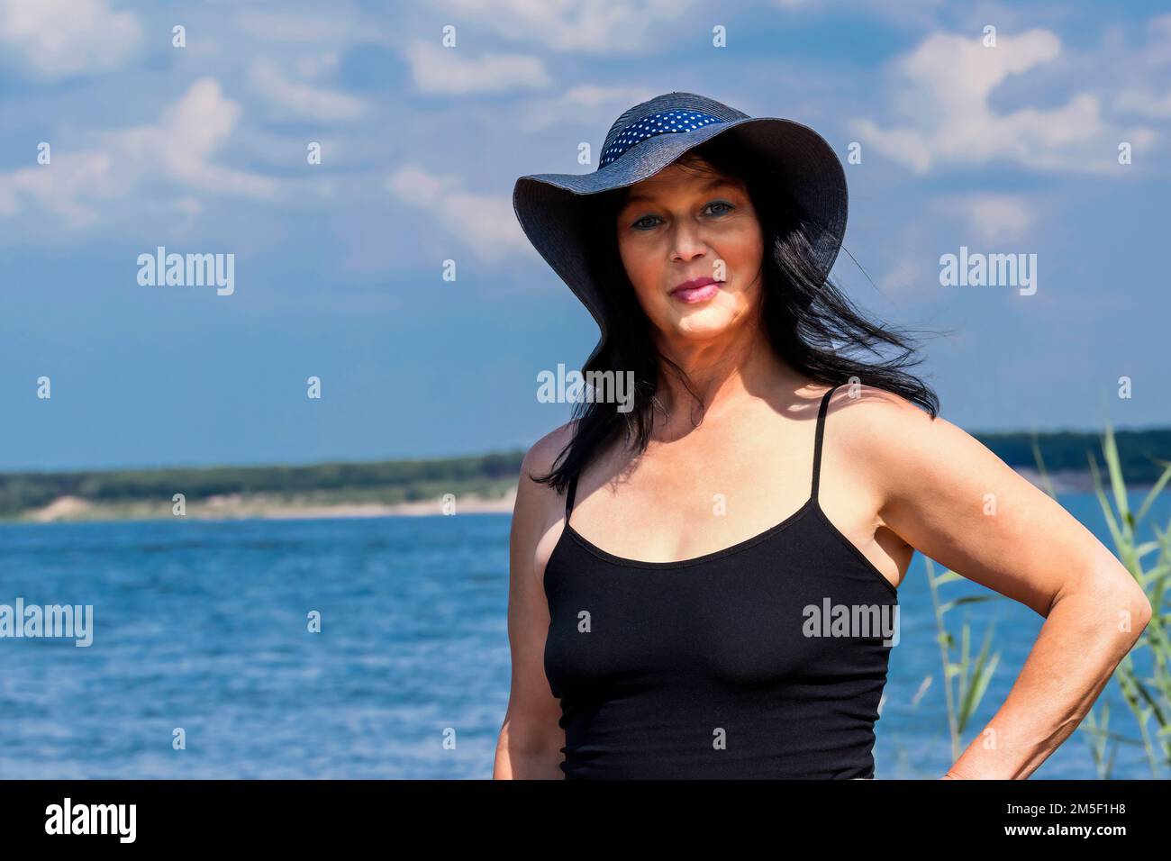 Older pretty woman with hat at lake Stock Photo