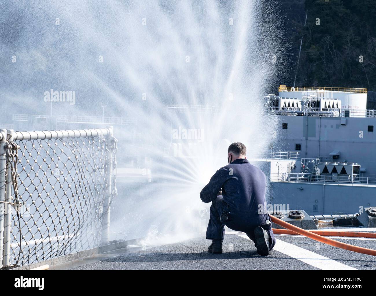 YOKOSUKA, Japan (March 9, 2022) - Damage Controlman 1st Class  Brandon Carrick, from Cathedral City, Calif., tests the fire hose prior to hose-handling training March 9, 2022 on the flight deck of U.S. 7th Fleet flagship USS Blue Ridge (LCC 19). Blue Ridge is the oldest operational ship in the Navy and, as 7th Fleet command ship, actively works to foster relationships with allies and partners in the Indo-Pacific region. Stock Photo