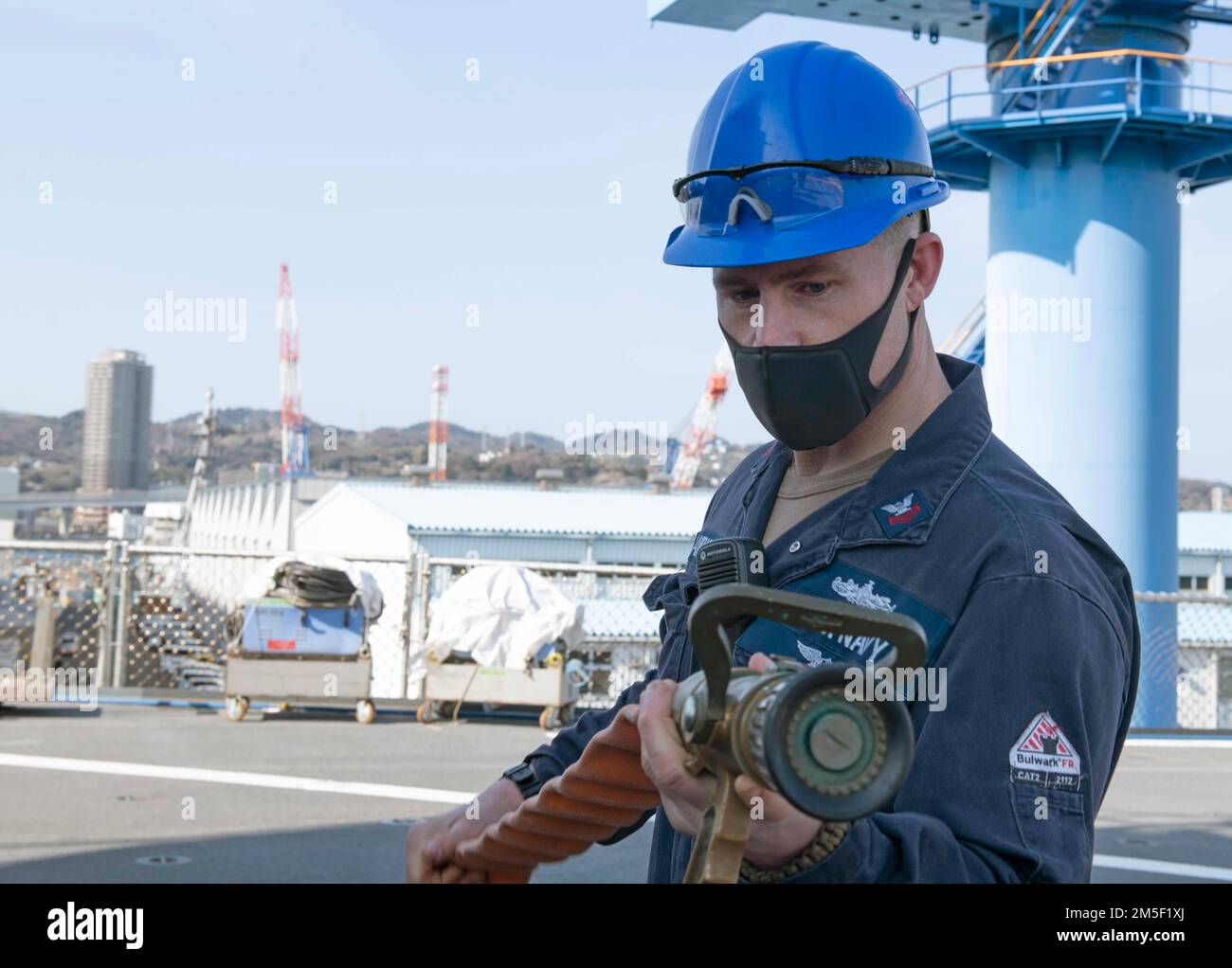 YOKOSUKA, Japan (March 9, 2022) - Damage Controlman 1st Class Brandon Carrick, from Cathedral City, Calif., demonstrates proper hose-handling techniques during training March 9, 2022 on the flight deck of U.S. 7th Fleet flagship USS Blue Ridge (LCC 19). Blue Ridge is the oldest operational ship in the Navy and, as 7th Fleet command ship, actively works to foster relationships with allies and partners in the Indo-Pacific region. Stock Photo