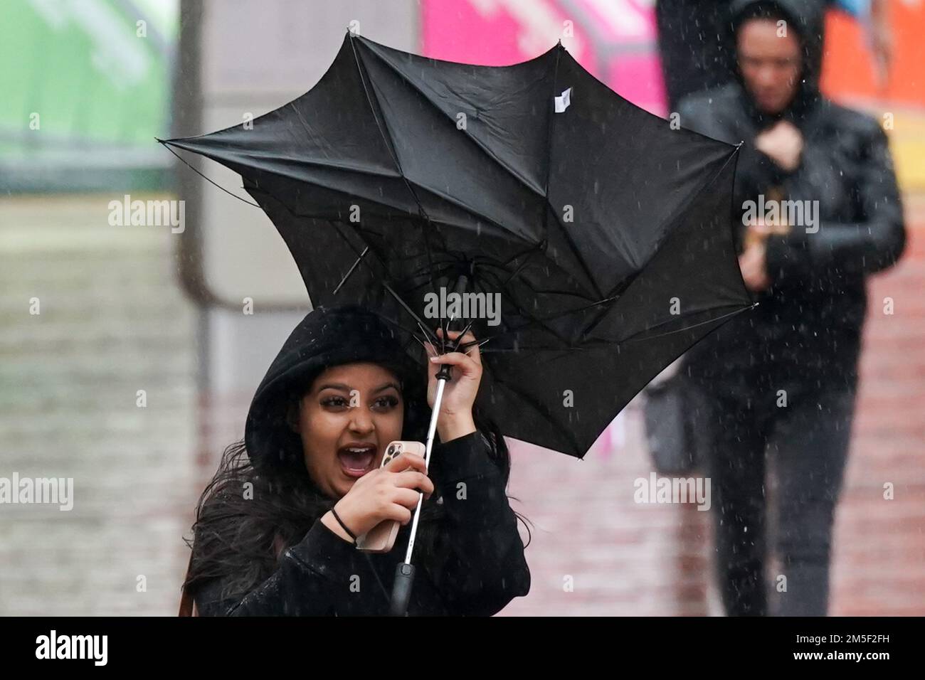 File photo dated 30/09/22 of a woman struggles with her umbrella during the wet and windy weather in Birmingham. The deadly bomb cyclone that has sent temperatures plunging in the US is also causing the UK to experience wet and windy weather, the Met Office said. On Wednesday, the forecaster issued a yellow weather warning for heavy rain from 3am on Friday for 15 hours for much of Scotland, including Edinburgh, Glasgow and Stirling. Issue date: Wednesday December 28, 2022. Stock Photo